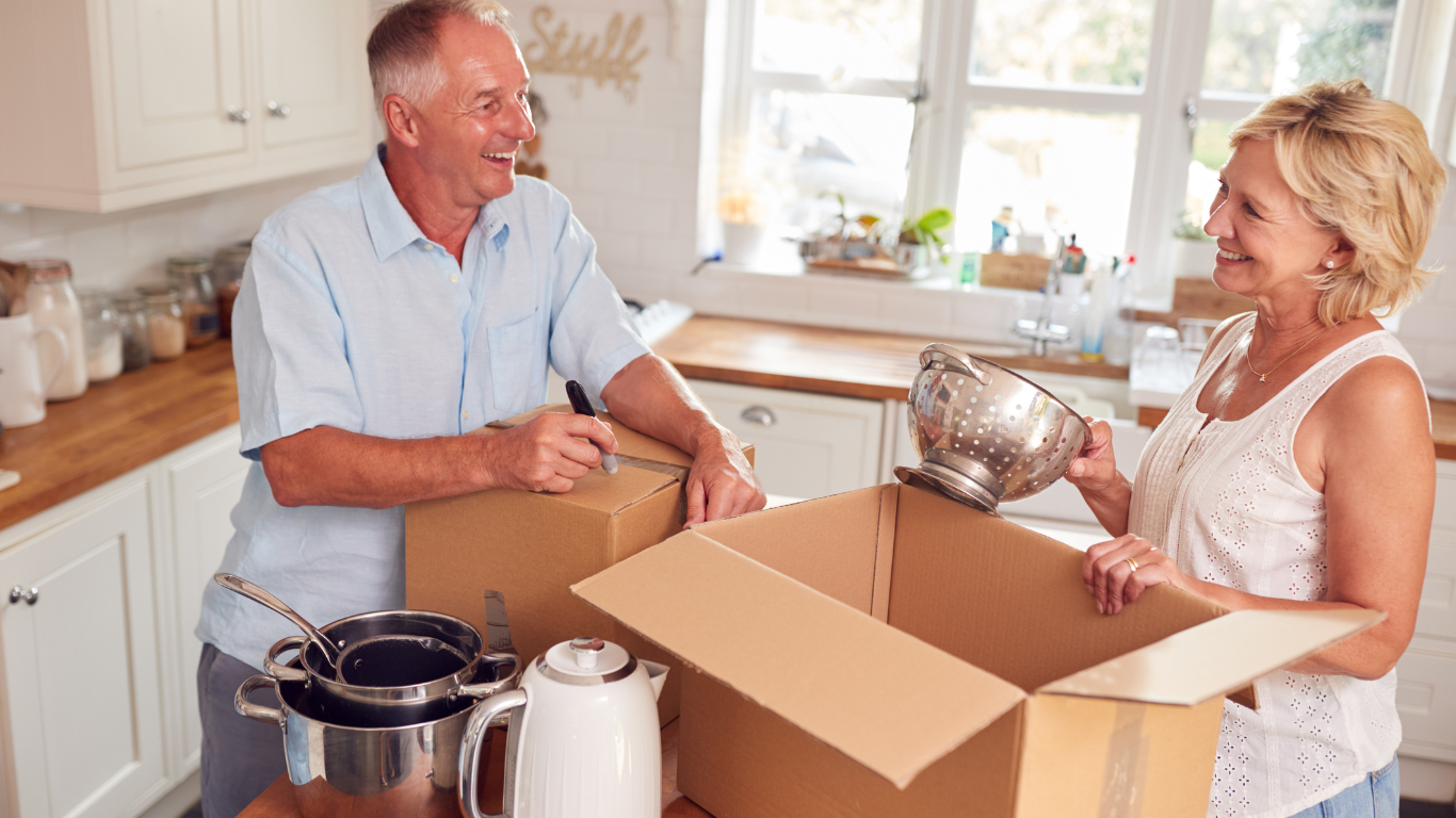 A man and a woman organize and box up kitchen items