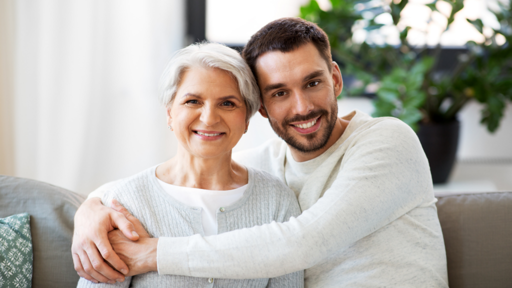 A son hugs his mom while they sit on the couch